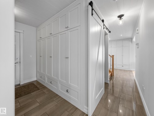 White shaker-style cabinetry with chrome hardware, wood-finish flooring, white shiplap ceiling, and a barn door with black hardware - 1223 Appleton Close, Sherwood Park, AB 