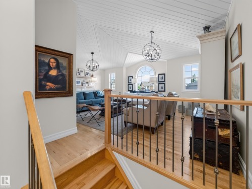 Vaulted ceilings with plank detailing, wood-finish flooring, staircase with natural wood handrail and wrought iron spindles, abundant natural light, and a prominent arched window - 1223 Appleton Close, Sherwood Park, AB 