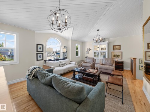 Vaulted plank ceiling, hardwood flooring, arched window, built-in display cabinet, and spherical chandeliers - 1223 Appleton Close, Sherwood Park, AB 
