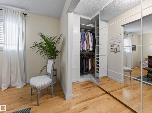 Custom built-in closet system with open shelving, mirrored closet doors, and wood-finish flooring - 1223 Appleton Close, Sherwood Park, AB 