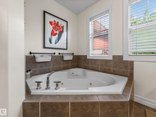 Corner soaking tub with chrome fixtures, surrounded by brown tile - 1223 Appleton Close, Sherwood Park, AB 
