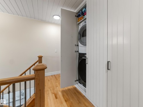 Hardwood flooring, painted paneled ceiling, wood newel post, metal balusters, and built-in stacked laundry appliances - 1223 Appleton Close, Sherwood Park, AB 