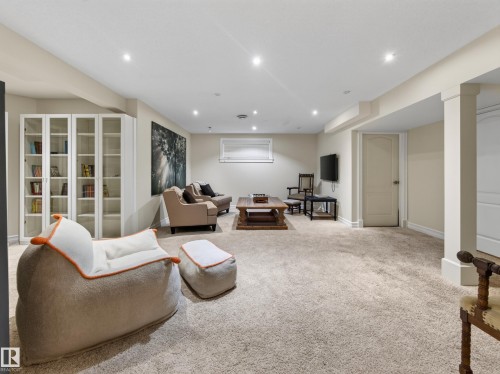Recessed lighting illuminates this carpeted living space, featuring built-in cabinetry with glass doors, a single window, and neutral-toned walls - 1223 Appleton Close, Sherwood Park, AB 