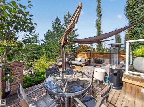 Expansive wood-finish deck with integrated privacy screening and a shade sail - 1223 Appleton Close, Sherwood Park, AB 