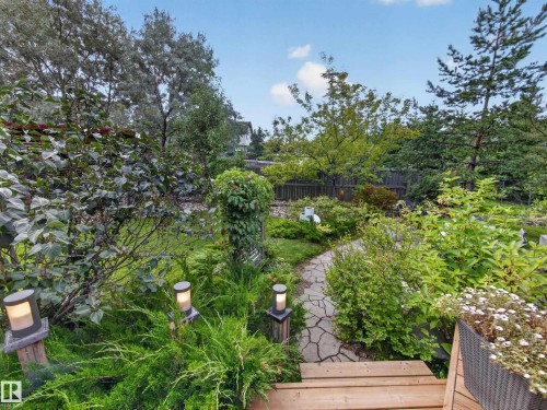 Manicured garden landscape featuring mature trees, a flagstone path, and integrated landscape lighting - 1223 Appleton Close, Sherwood Park, AB 