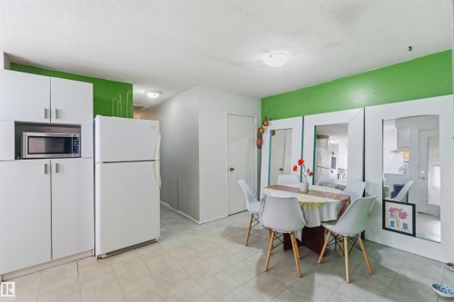 White cabinetry with integrated microwave, white refrigerator, and light tile flooring - 13408 67 Street Nw, Edmonton, AB 