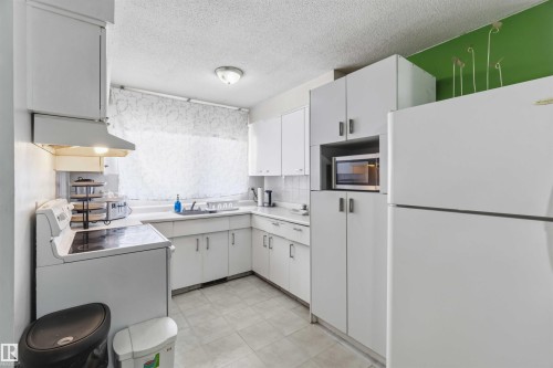 White cabinetry with integrated microwave, white tiled flooring, and a white countertop - 13408 67 Street Nw, Edmonton, AB 