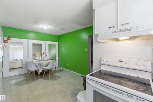 White cabinetry, electric range with overhead exhaust, overhead lighting, and tile flooring - 13408 67 Street Nw, Edmonton, AB 