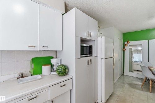 White cabinetry with integrated microwave, white appliances, and a tiled countertop - 13408 67 Street Nw, Edmonton, AB 