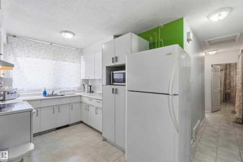 Kitchen featuring white cabinetry, white countertops, built-in microwave, and tile flooring - 13408 67 Street Nw, Edmonton, AB 
