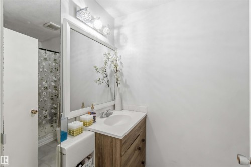 Vanity with a wood-finish cabinet, white countertop, and integrated sink - 13408 67 Street Nw, Edmonton, AB 