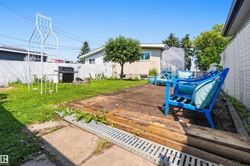Expansive backyard with a level lawn, concrete patio, and a dedicated wooden patio area - 13408 67 Street Nw, Edmonton, AB 