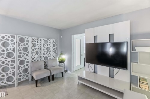Tile flooring, light gray wall paint, white room divider with circular pattern, white built-in media console, white open shelving unit - 13408 67 Street Nw, Edmonton, AB 