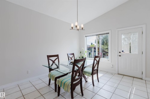 Vaulted ceiling, white tile flooring, large window with exterior scenery, white exterior door with glass insert, and a modern ceiling light fixture - 8517 156 Avenue Nw, Edmonton, AB 