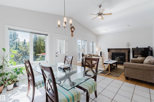 Vaulted ceiling with an attached fan, a fireplace with a dark stone surround, and wood-finish flooring - 8517 156 Avenue Nw, Edmonton, AB 