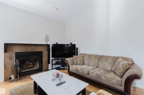 Vaulted ceiling with recessed lighting, tile-surround fireplace, wood-finish flooring, and white wall finishes - 8517 156 Avenue Nw, Edmonton, AB 