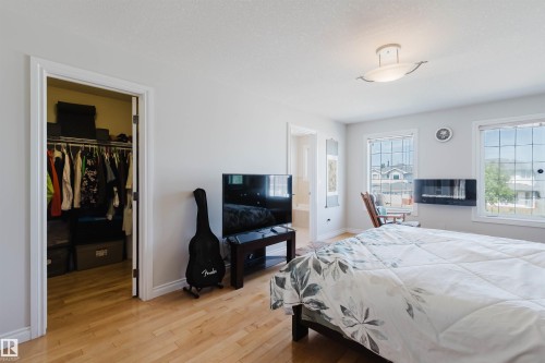 Hardwood-finish flooring, built-in closet with shelving and hanging rods, ceiling-mounted light fixture, two windows, and a wall-mounted fireplace - 8517 156 Avenue Nw, Edmonton, AB 