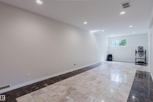 Recessed lighting illuminates the spacious room with light-toned walls and contrasting floor tiling - 8517 156 Avenue Nw, Edmonton, AB 
