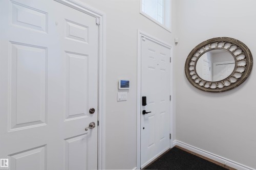 White paneled interior doors, wall-mounted smart thermostat, and high ceilings with transom window - 8517 156 Avenue Nw, Edmonton, AB 