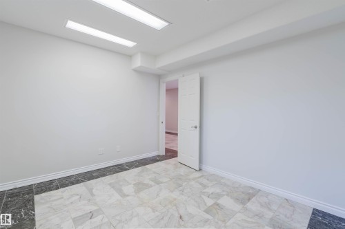 Recessed lighting fixtures, white paneled door, light-toned wall finishes, and patterned tile flooring with dark border - 8517 156 Avenue Nw, Edmonton, AB 