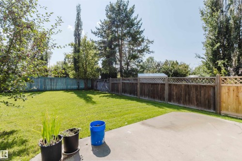 Expansive backyard featuring a manicured lawn, concrete patio, and a combination of wood and lattice fencing - 8517 156 Avenue Nw, Edmonton, AB 