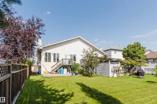 Spacious backyard with manicured lawn, full-height privacy fencing, and a concrete patio - 8517 156 Avenue Nw, Edmonton, AB 