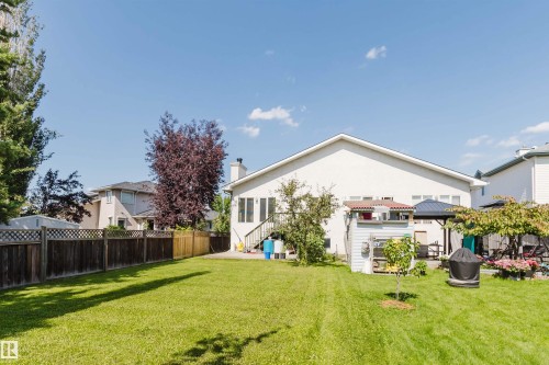 Expansive backyard featuring a manicured lawn, mature trees, and a privacy fence - 8517 156 Avenue Nw, Edmonton, AB 