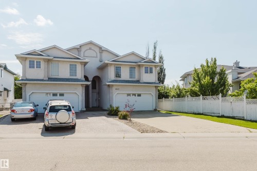 Stucco exterior with arched entry, two single-car garages, and paved driveways - 8517 156 Avenue Nw, Edmonton, AB 