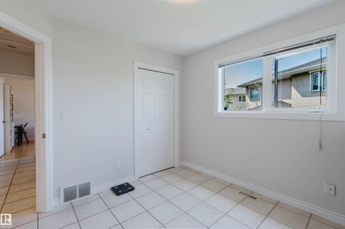 Tile flooring, white bi-fold closet doors, white trim, and a window with white casing - 8517 156 Avenue Nw, Edmonton, AB 
