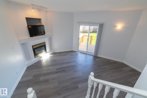 Fireplace with a mantel, wood-finish flooring, sliding glass door, deck, and railing - #37 3811 85 St Nw, Edmonton, AB 
