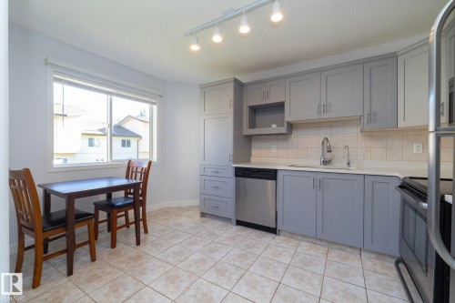 Kitchen featuring light gray cabinetry, white countertops, stainless steel dishwasher, tile flooring, and a large window - #37 3811 85 St Nw, Edmonton, AB 