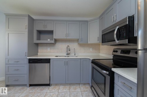 Kitchen featuring light gray cabinetry, white countertops, tile backsplash, and stainless steel appliances - #37 3811 85 St Nw, Edmonton, AB 