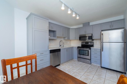 Kitchen featuring light gray cabinetry, white countertops, stainless steel appliances, ceramic tile flooring, and a white subway tile backsplash - #37 3811 85 St Nw, Edmonton, AB 