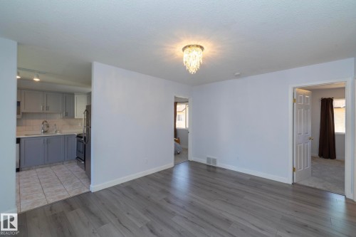 Wood-finish flooring, overhead chandelier, light gray walls, kitchen with gray cabinetry, and tile flooring - #37 3811 85 St Nw, Edmonton, AB 