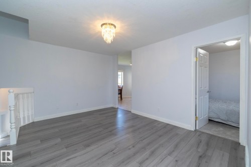 Wood-finish flooring throughout, white painted walls, and a crystal chandelier - #37 3811 85 St Nw, Edmonton, AB 