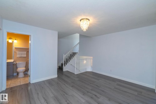 Wood-finish flooring, staircase with white railings, and a crystal chandelier - #37 3811 85 St Nw, Edmonton, AB 