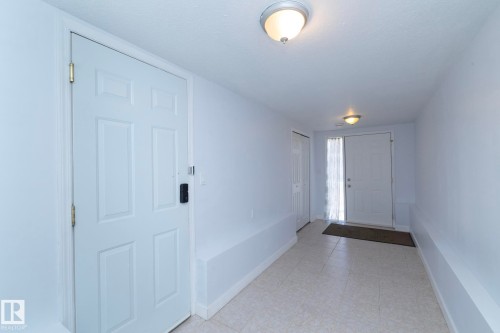 Entryway with neutral tile flooring, two ceiling-mounted light fixtures, and white paneled doors - #37 3811 85 St Nw, Edmonton, AB 