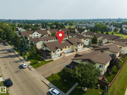 Townhome-style residences with attached garages, individual entrances, and surrounding green spaces - #37 3811 85 St Nw, Edmonton, AB 
