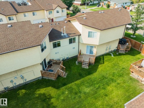 Expansive backyard featuring a manicured lawn, multiple wood decks, and a privacy fence - #37 3811 85 St Nw, Edmonton, AB 