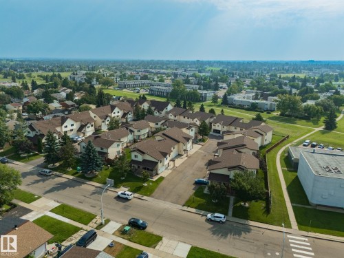 Residential community featuring townhomes with attached garages, surrounded by expansive green spaces and paved pathways - #37 3811 85 St Nw, Edmonton, AB 