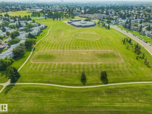 Expansive green space featuring a paved walking path, open fields, and surrounding residential structures - #37 3811 85 St Nw, Edmonton, AB 