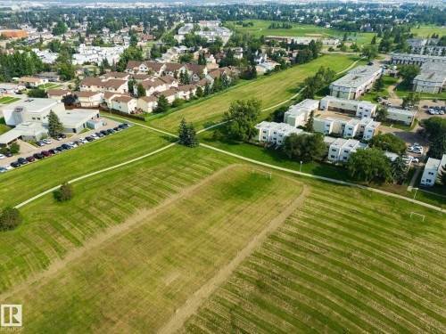 Expansive green spaces with pedestrian pathways, bordered by residential structures and mature trees - #37 3811 85 St Nw, Edmonton, AB 