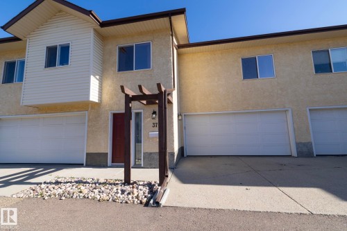 Stucco exterior with a peaked roofline and horizontal siding accent - #37 3811 85 St Nw, Edmonton, AB 