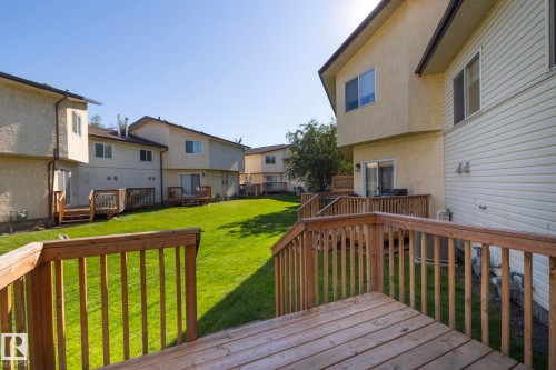 Wood decking with railings, stucco and siding exterior, sliding glass doors, upper-level windows, and a manicured lawn - #37 3811 85 St Nw, Edmonton, AB 