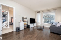 Spacious living area featuring wood-finish flooring, light-colored walls, and a large window - 