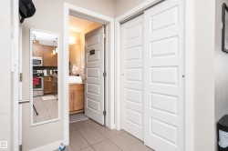 Hallway featuring tile flooring, white paneled doors, and a built-in closet with sliding doors - 