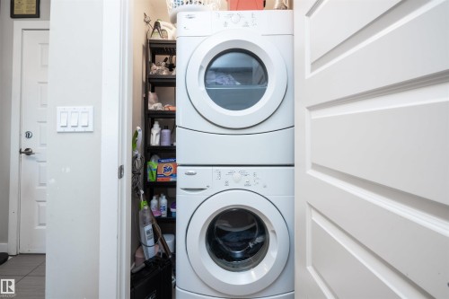 Dedicated laundry area featuring a stacked washer and dryer unit - #610 5151 Windermere Bv Sw, Edmonton, AB - Indoor Photo Showing Laundry Room