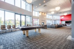 Spacious common area featuring large windows, patterned carpeting, a central fireplace, and diverse seating arrangements - 