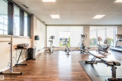 Dedicated fitness room featuring wood-finish flooring and multiple exercise machines - 