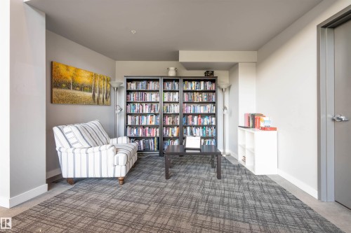 Living area featuring a patterned carpet, built-in shelving, and light gray walls - #610 5151 Windermere Bv Sw, Edmonton, AB - Indoor Photo Showing Other Room